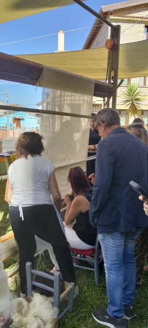 Partecipanti riuniti attorno al telaio negli spazi all’aperto.